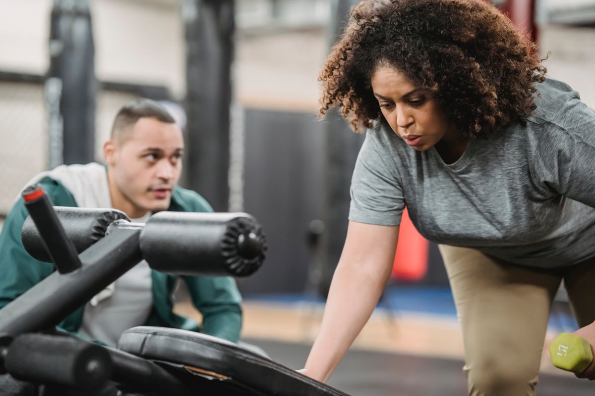 Trainer coaching a client through a core exercise on gym equipment