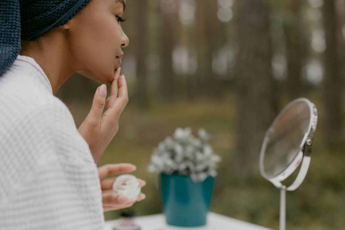 Woman applying face cream in a forest-side setting