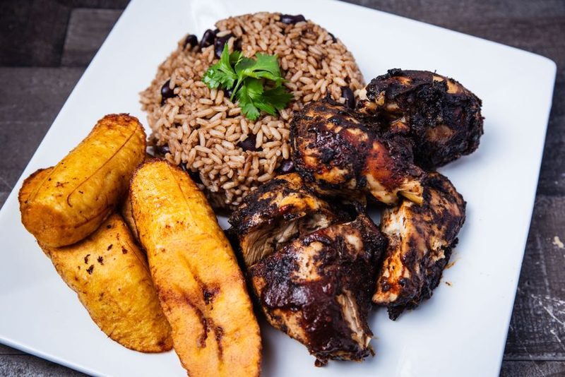 A plate of jerk chicken, rice, and fried plantain