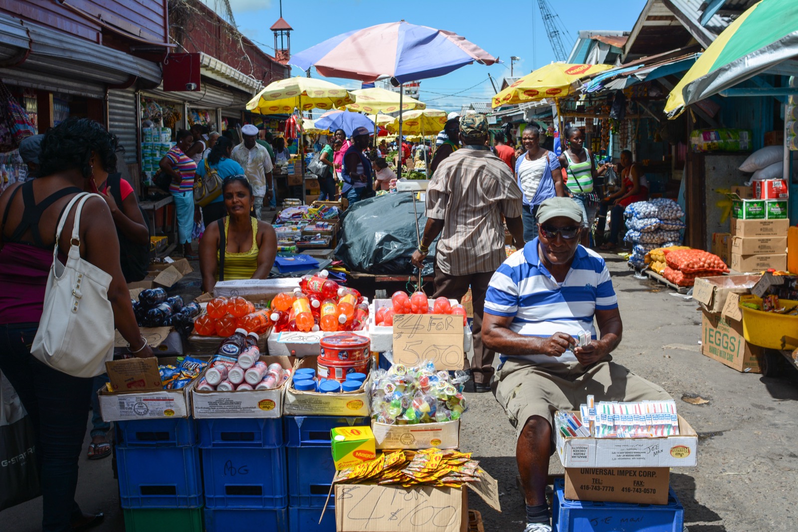 A narrow market lane lined with vendor stalls selling snacks and drinks