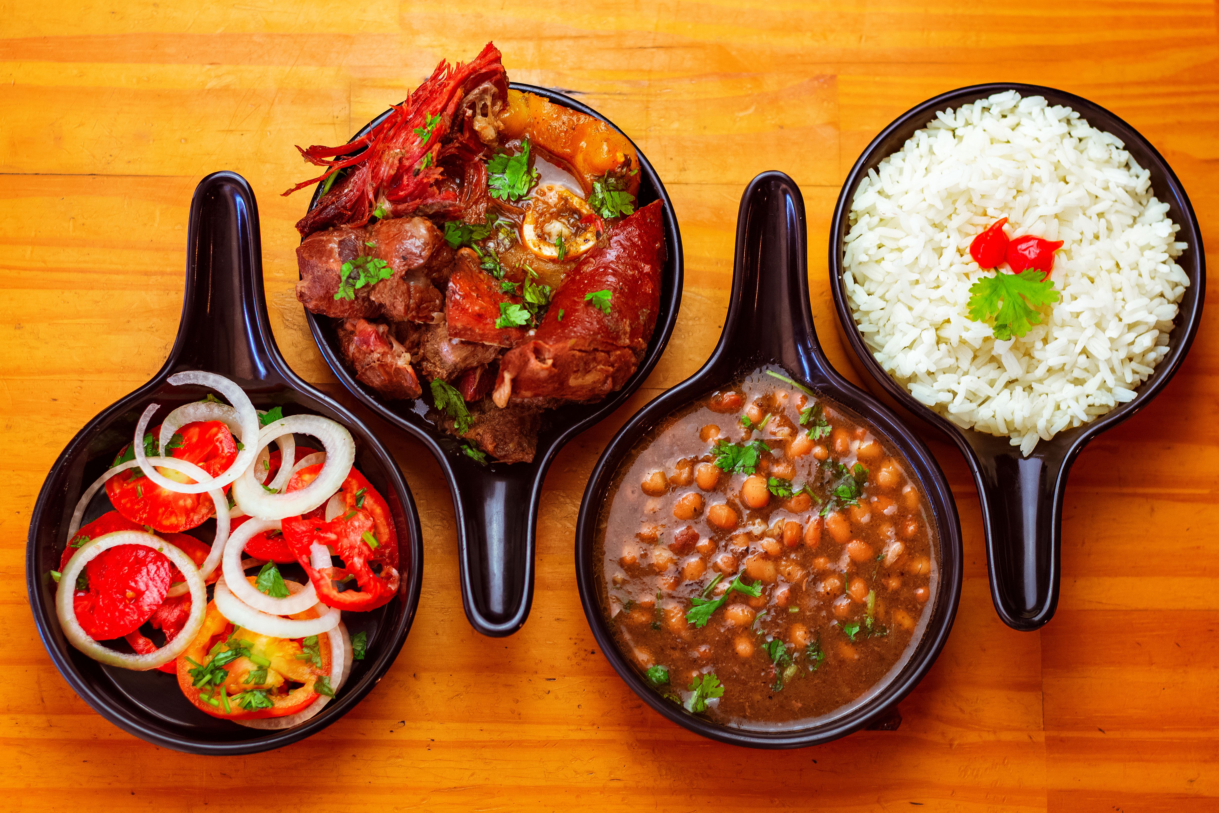 A Guyanese meal spread of white rice, stewed peas, tomato salad and stewed meat