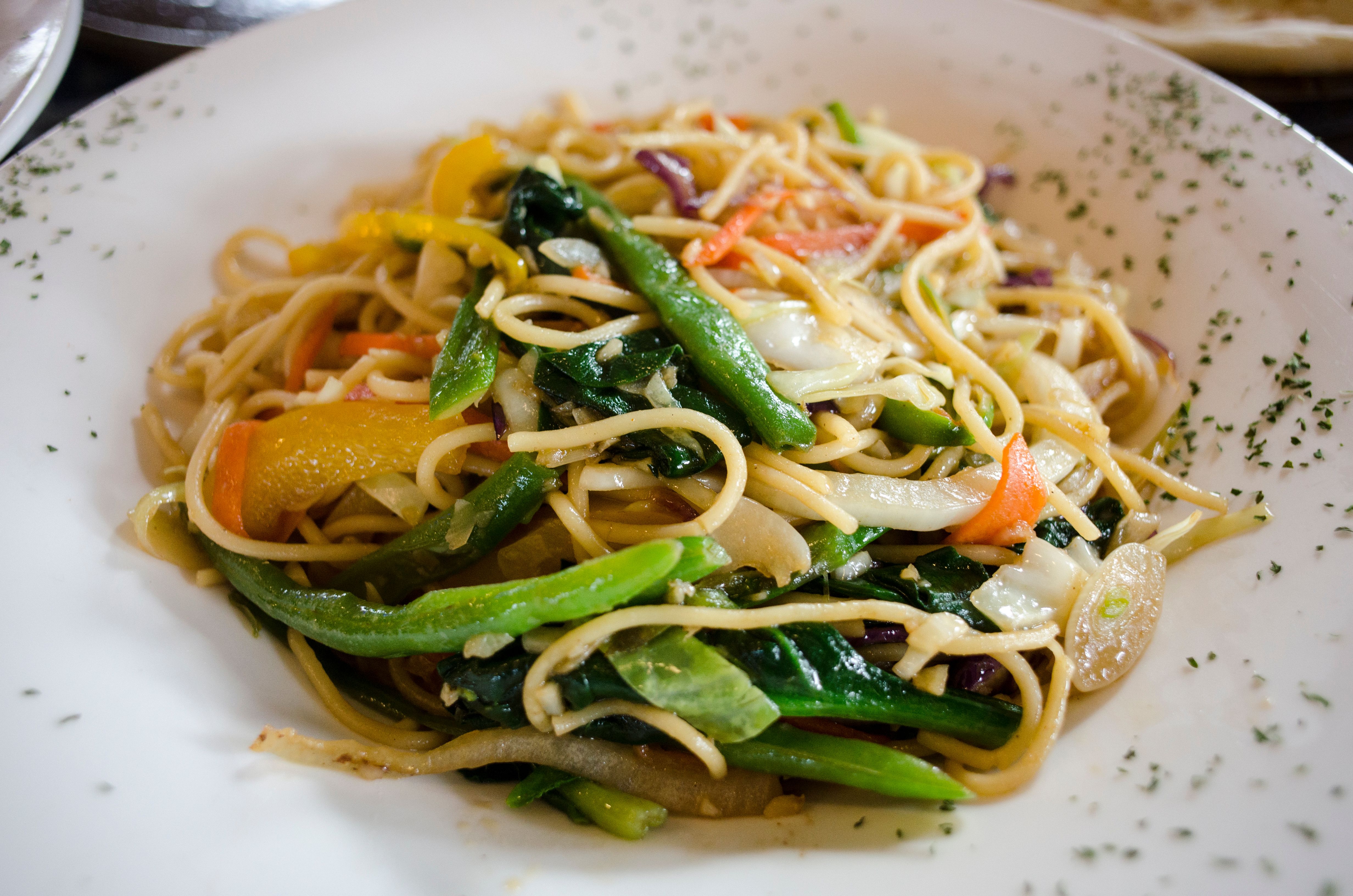 A plate of vegetable chow mein noodles with cabbage, carrots and peppers