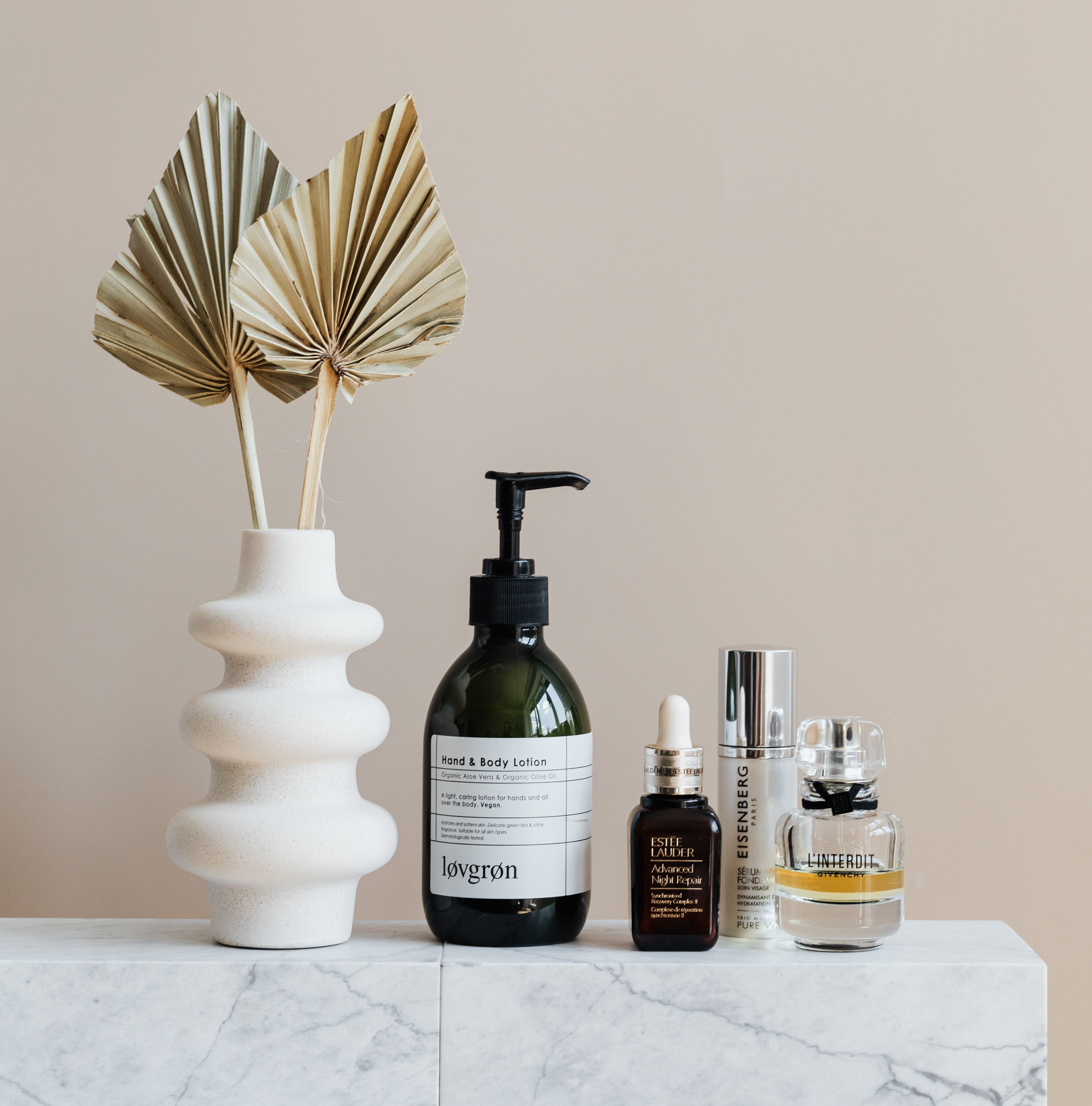 Skincare bottles and jars styled on a marble shelf