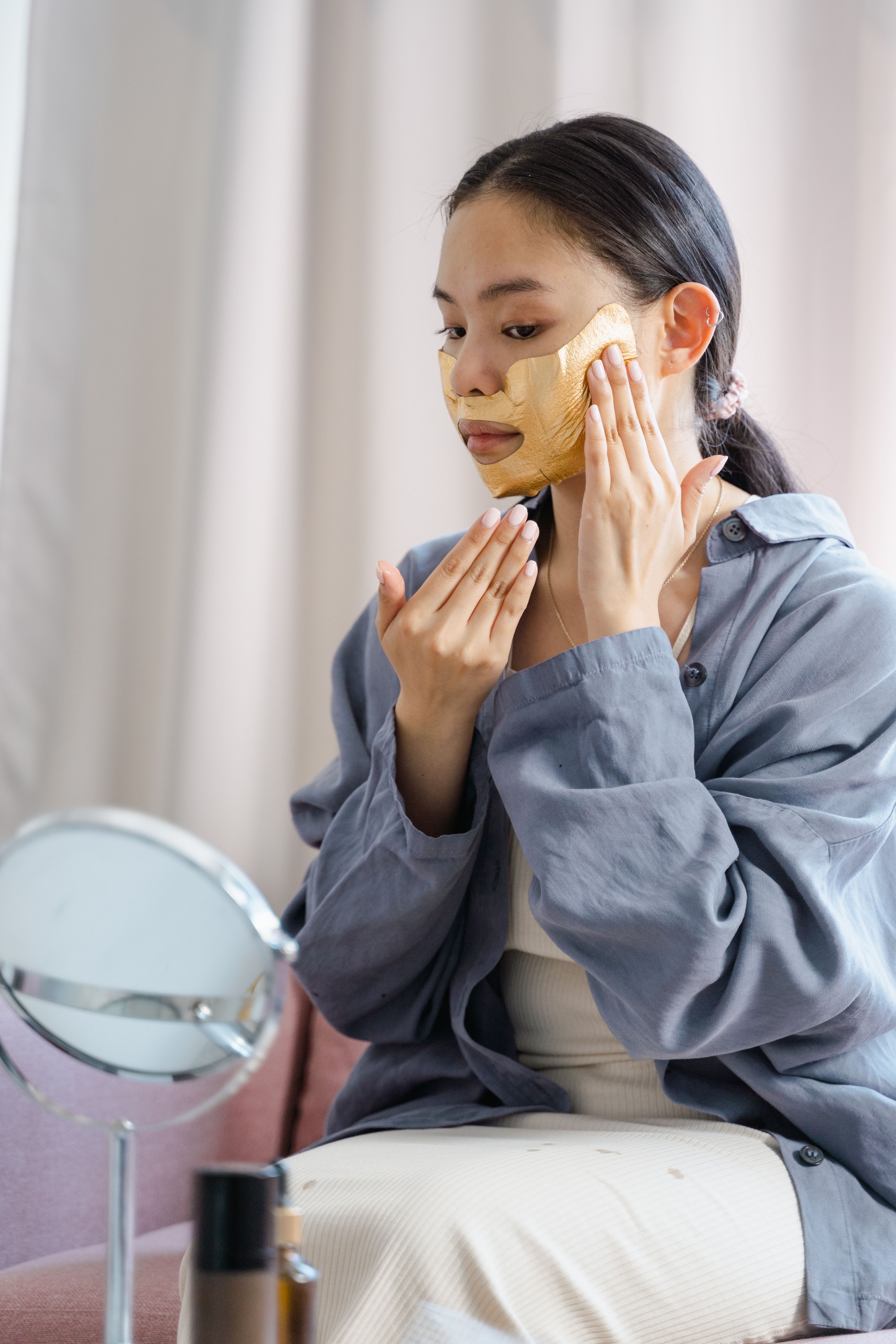 Woman applying a gold treatment mask to her cheek