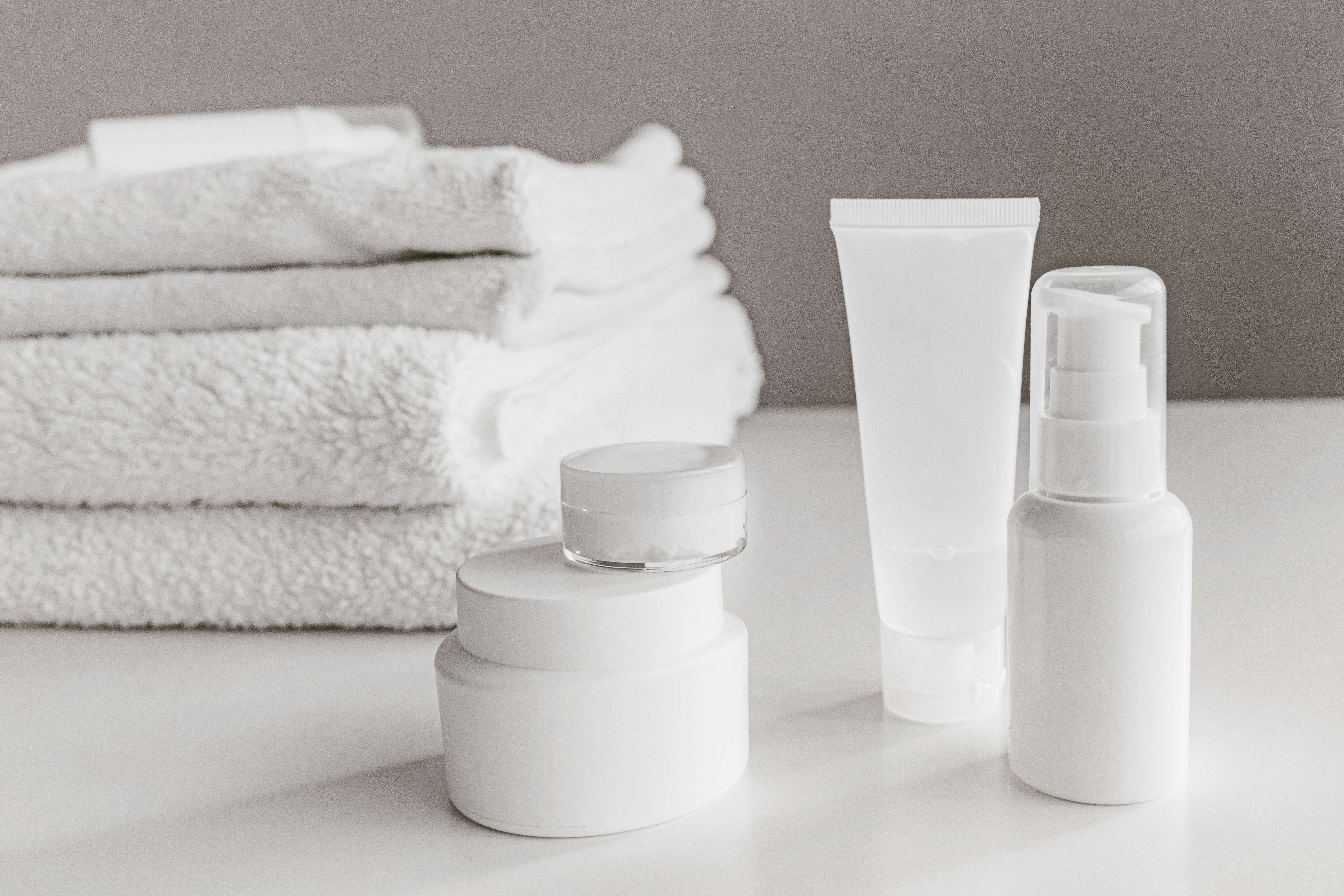 Minimalist white skincare bottles and jars on a neutral surface