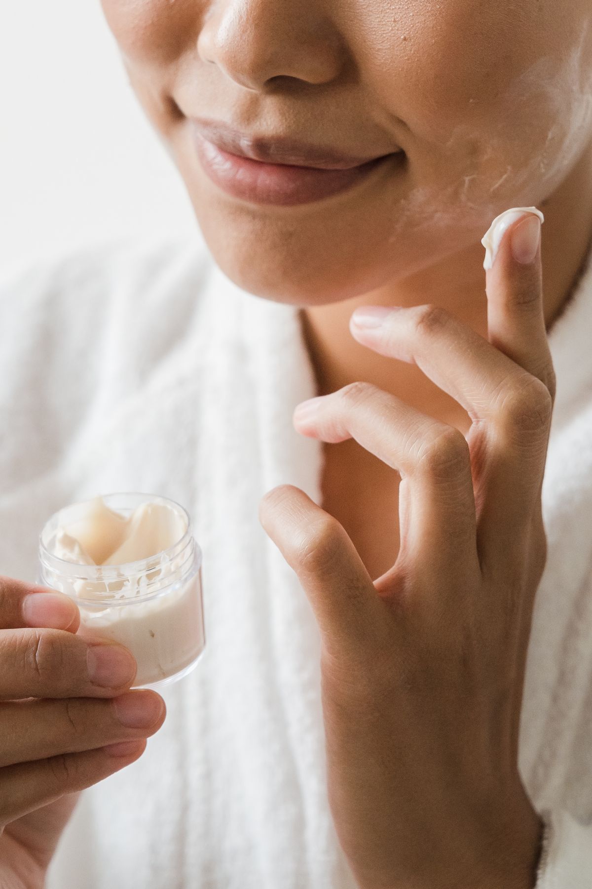 Woman smiling while applying face cream