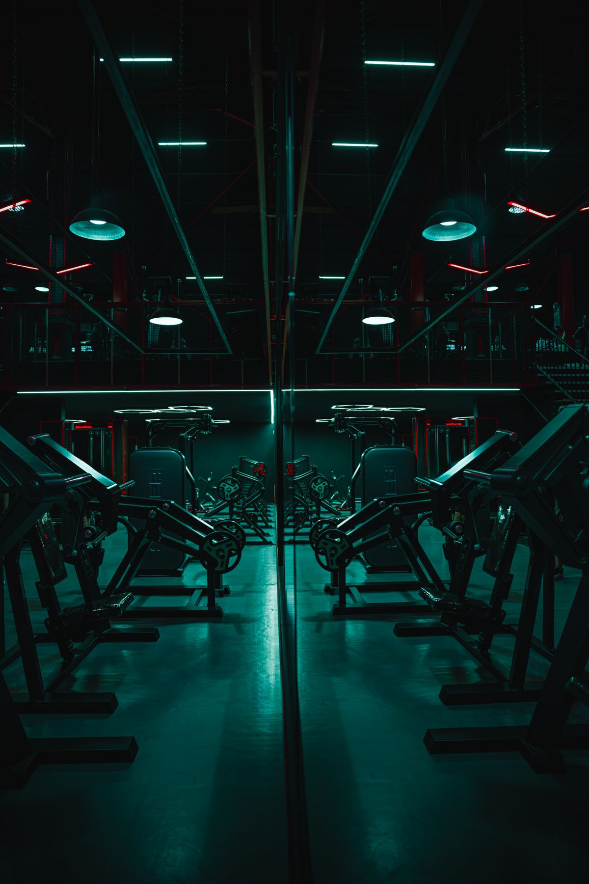 Mirrored view of the strength machine floor lit in cool blue and red light