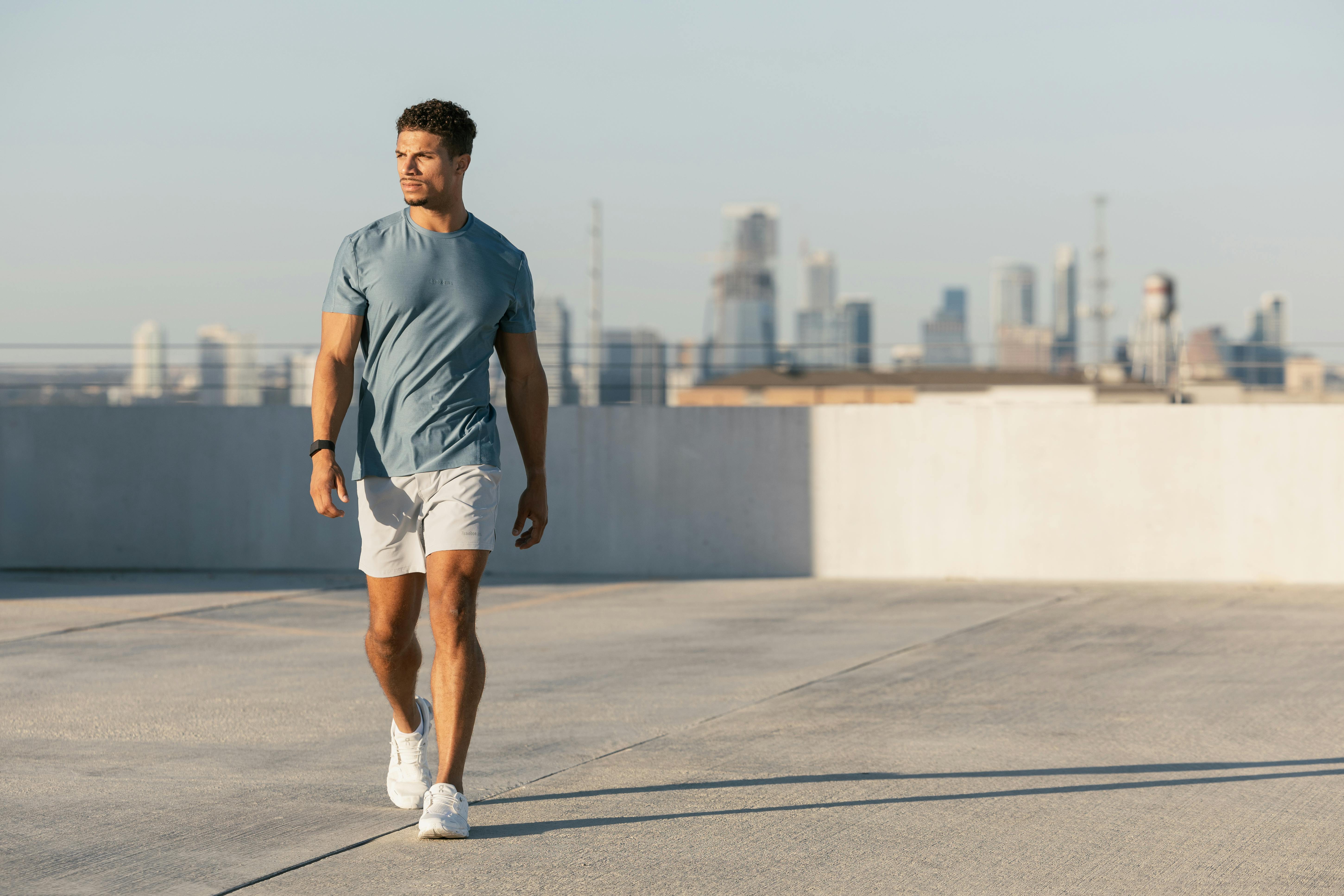 Member walking on a rooftop with the city skyline behind him