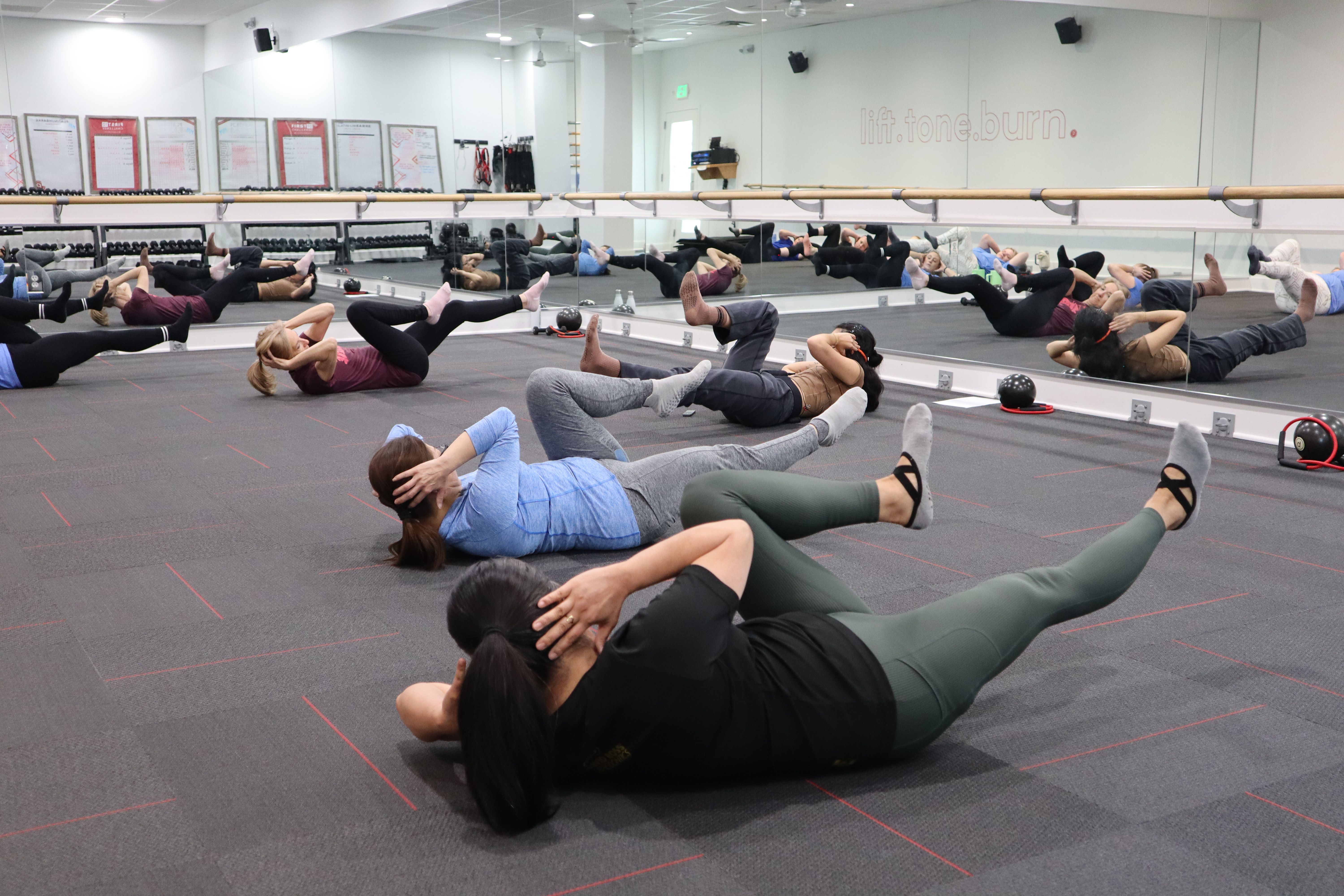 Members performing floor core exercises in a mirrored studio