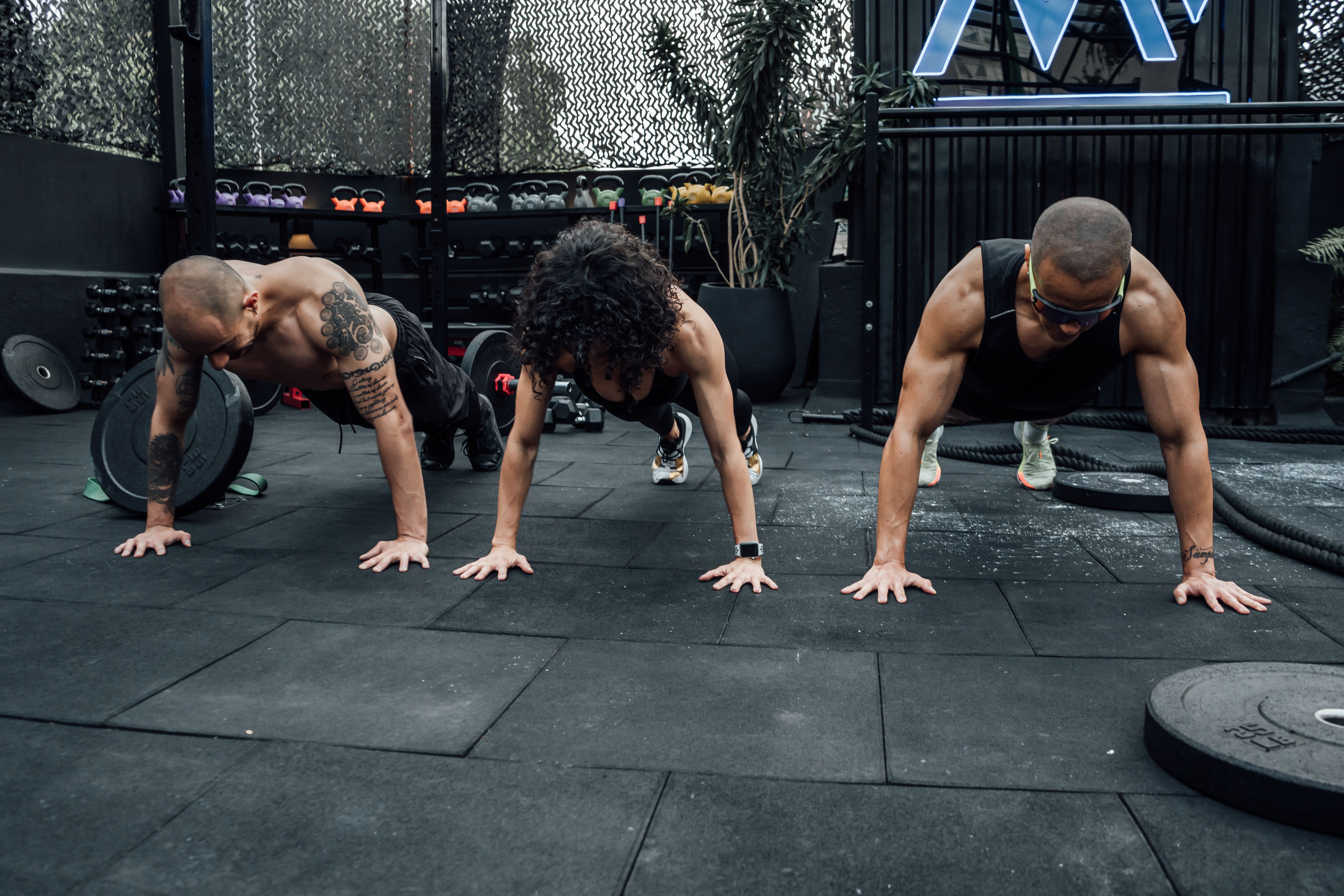 Three members doing push-ups together on an outdoor training deck