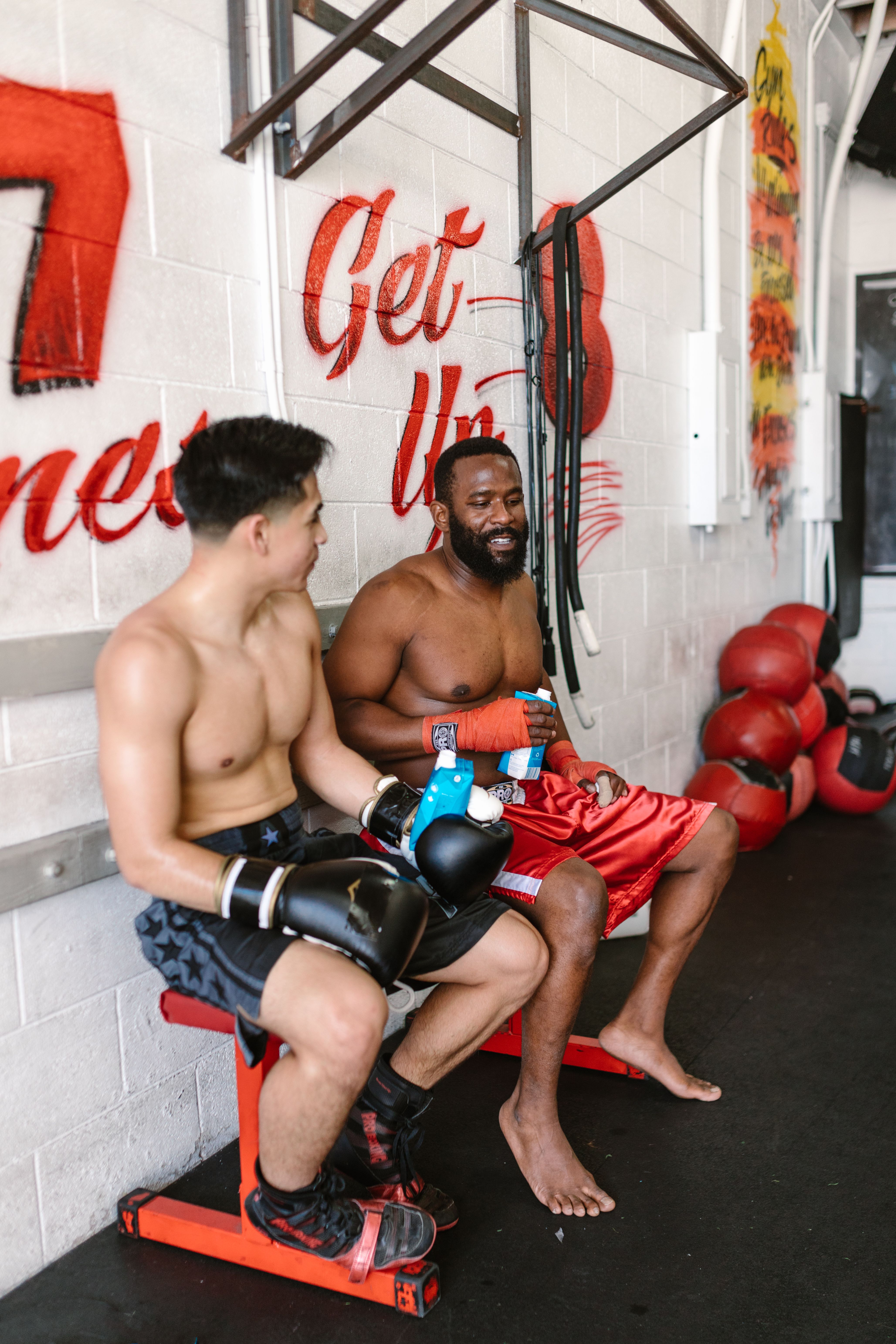 Two boxers wrapped and gloved up, resting between rounds