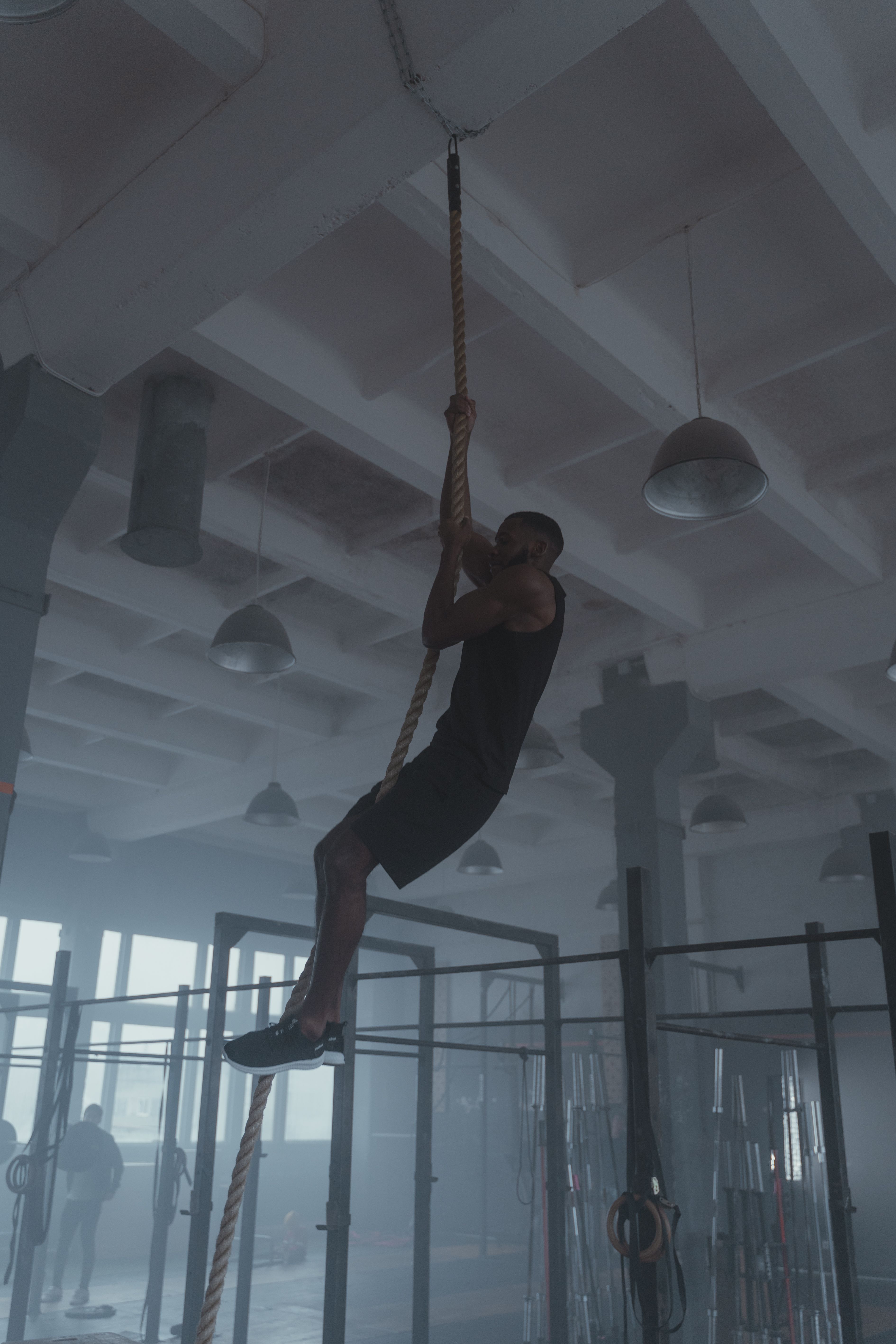 Member climbing a rope in an industrial-style gym