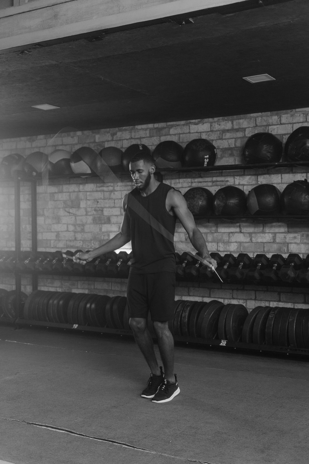 Athlete mid jump rope session in a moody black and white gym